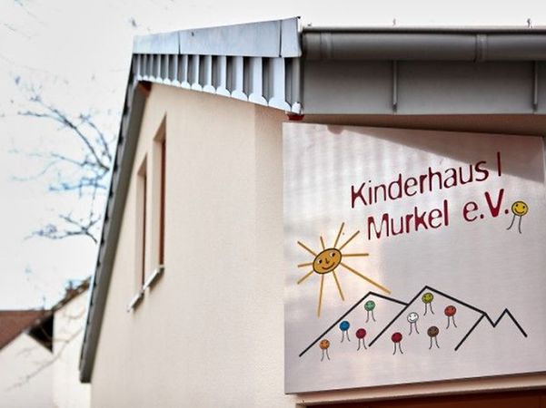 helle Aussenwand des Kinderhaus 1 mit buntem Logo des Murkel e.V.