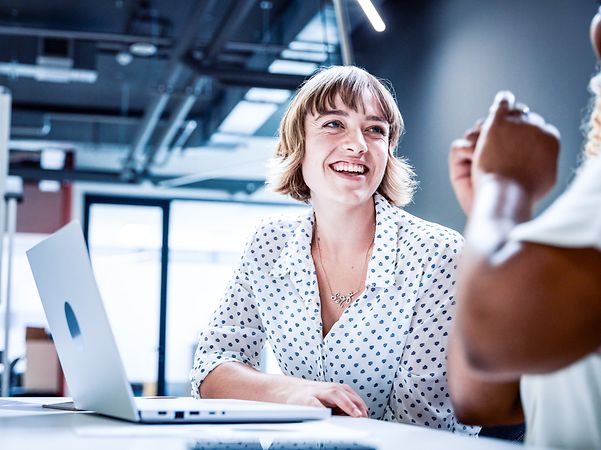 Geschäftsleute in Businesskleidung lächeln während der Diskussion bei einem Treffen im Büro